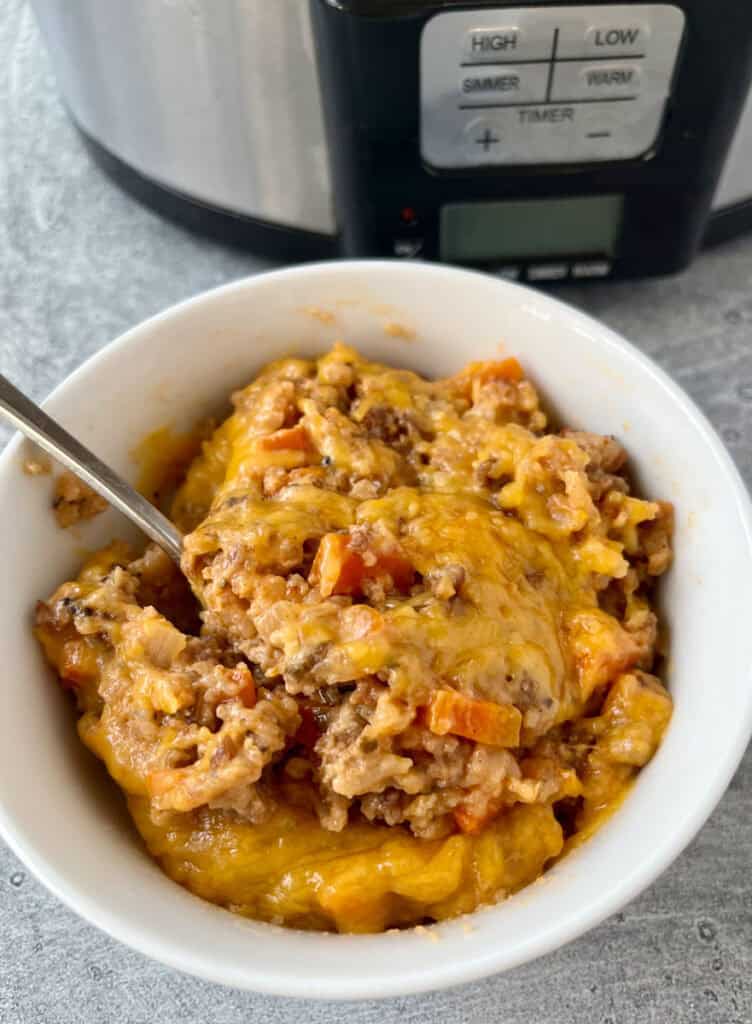 White bowl with ground pork casserole. There is a spoon in the bowl