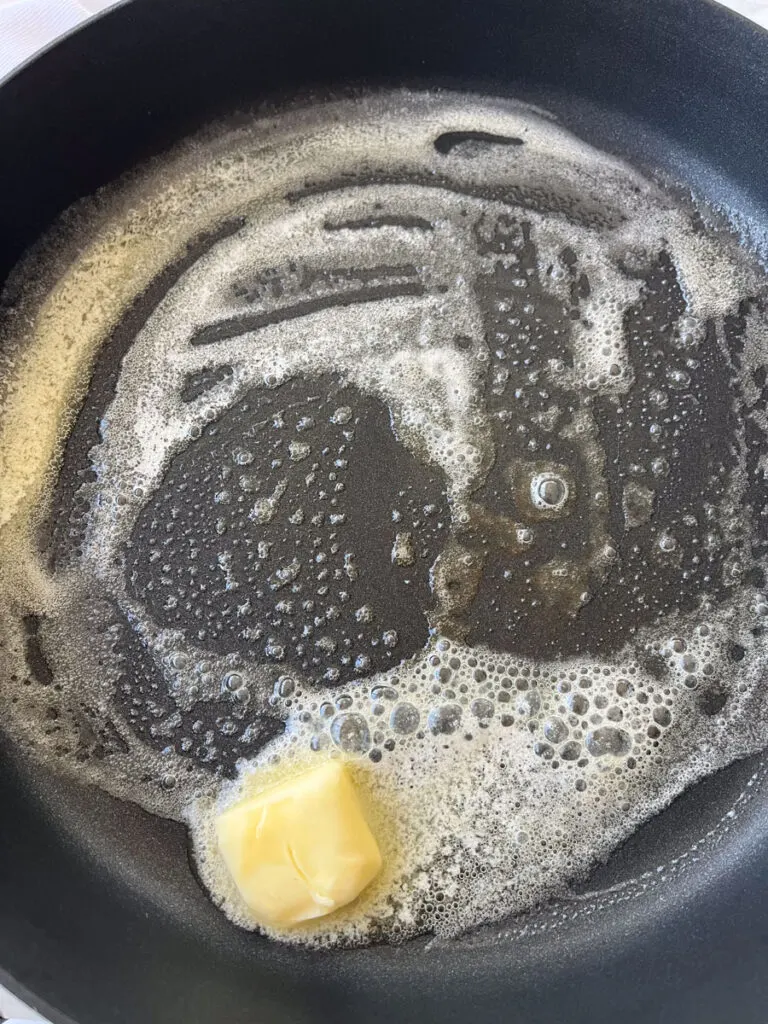 There is a large dark gray pan with butter melting in it.