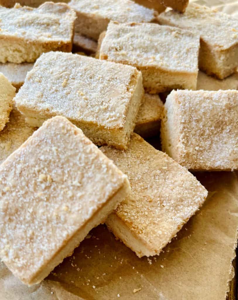 There are pieces of shortbread on a piece of light brown parchment paper.
