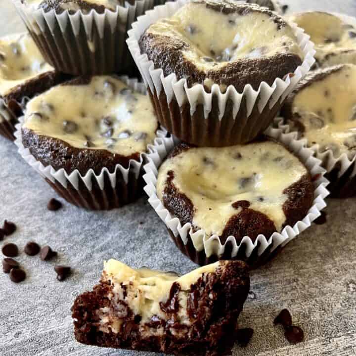 Group of black bottom cupcakes and mini chocolate chips on a light gray surface.