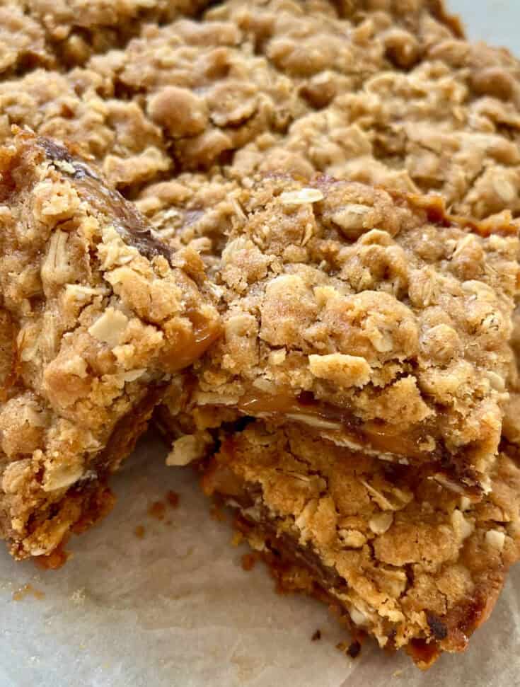 There is a pile of oatmeal layered bar cookies on a piece of white paper.