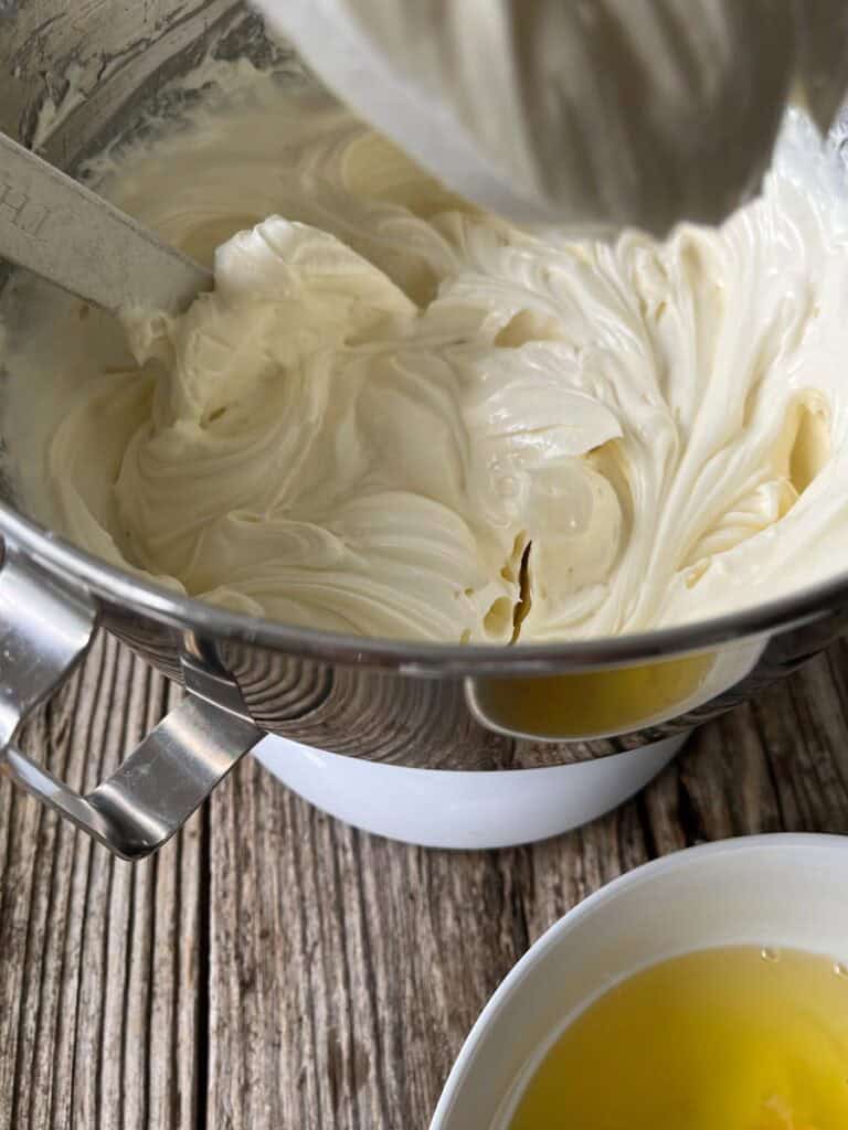 A bowl of a cream cheese mixture next to a bowl of eggs.