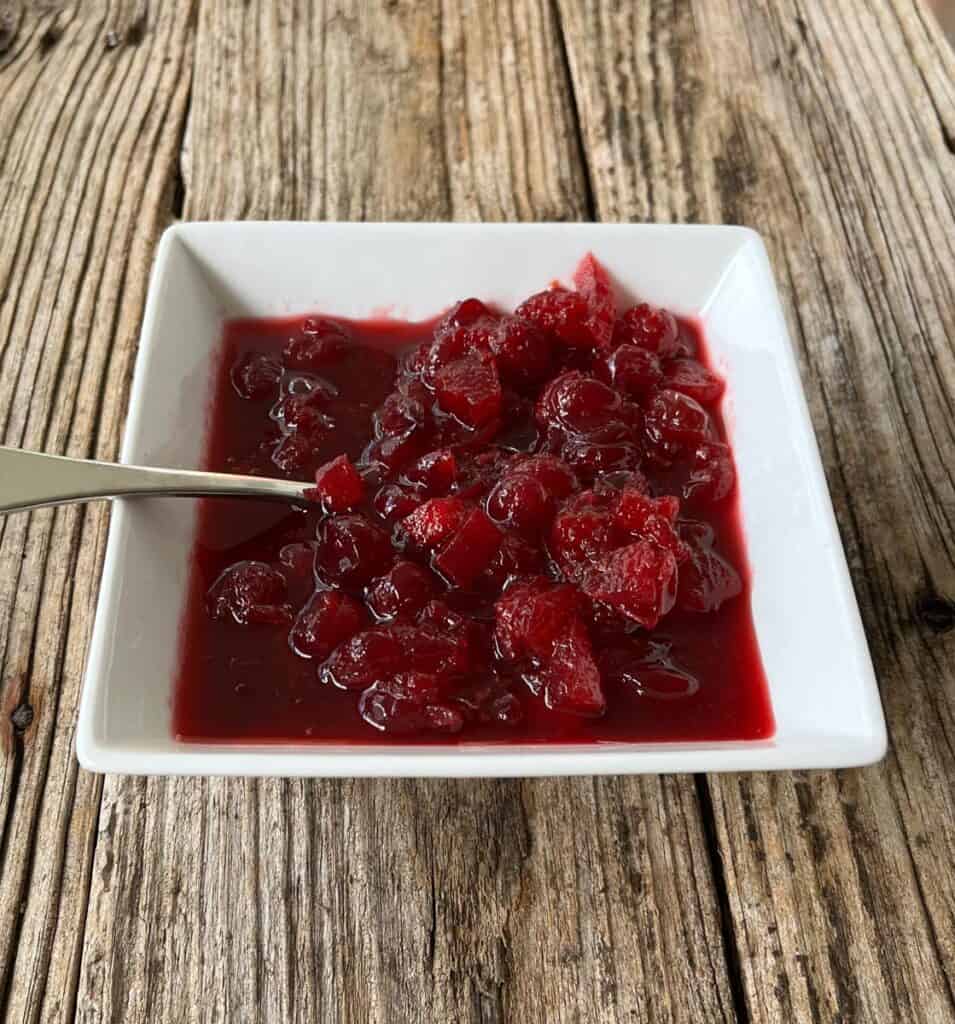 A bowl of cranberry sauce with a spoon.