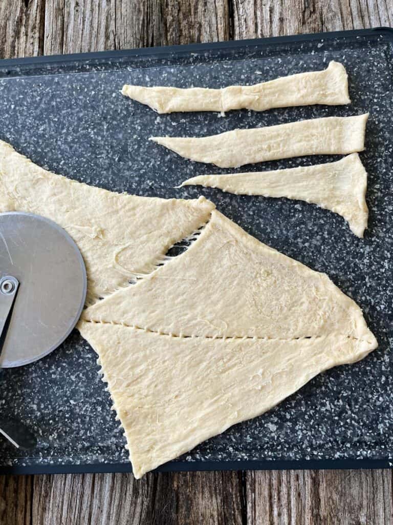 A cutting board with a piece of dough and a knife.