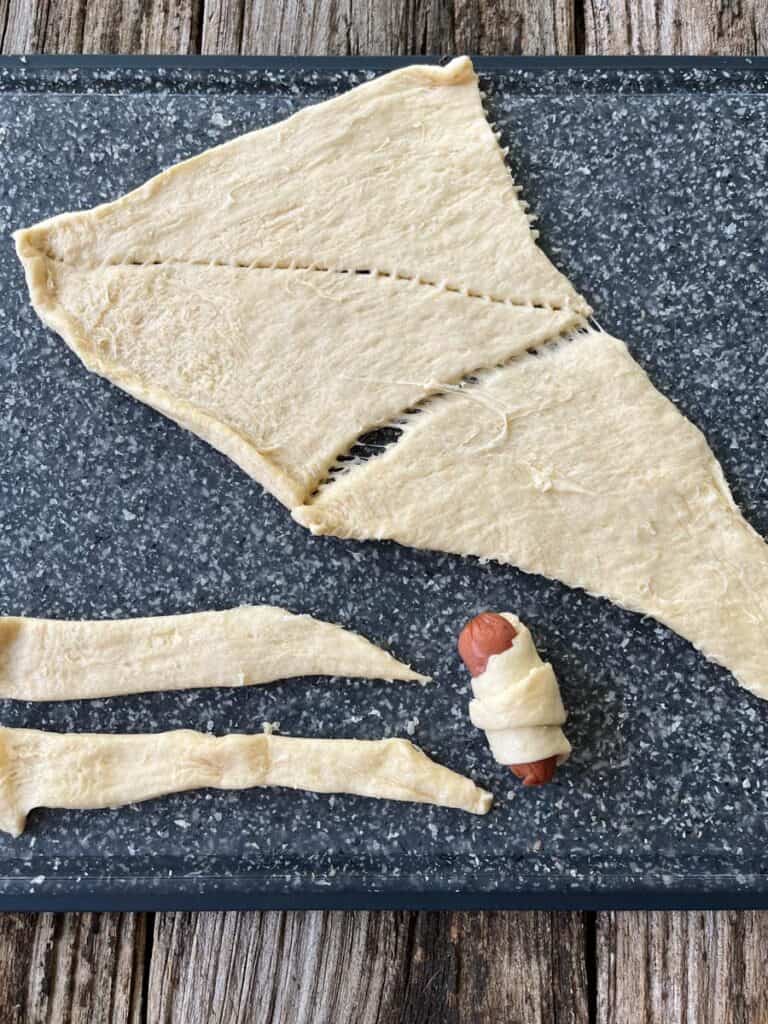 A piece of dough with a hot dog on it.