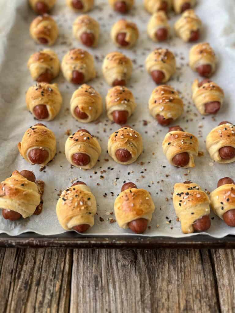 A baking sheet filled with small hot dogs.