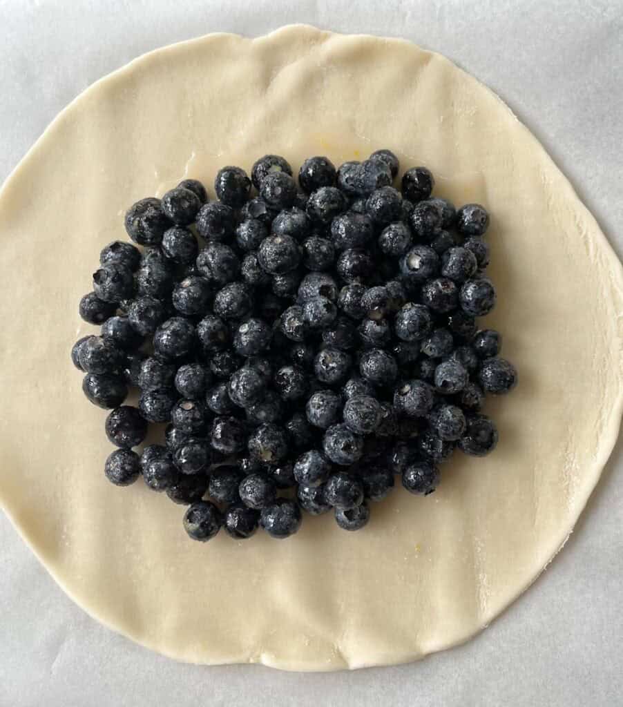 Blueberries in a circle on a pastry disk.