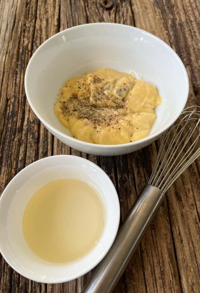 Two bowls with sauce and a whisk.