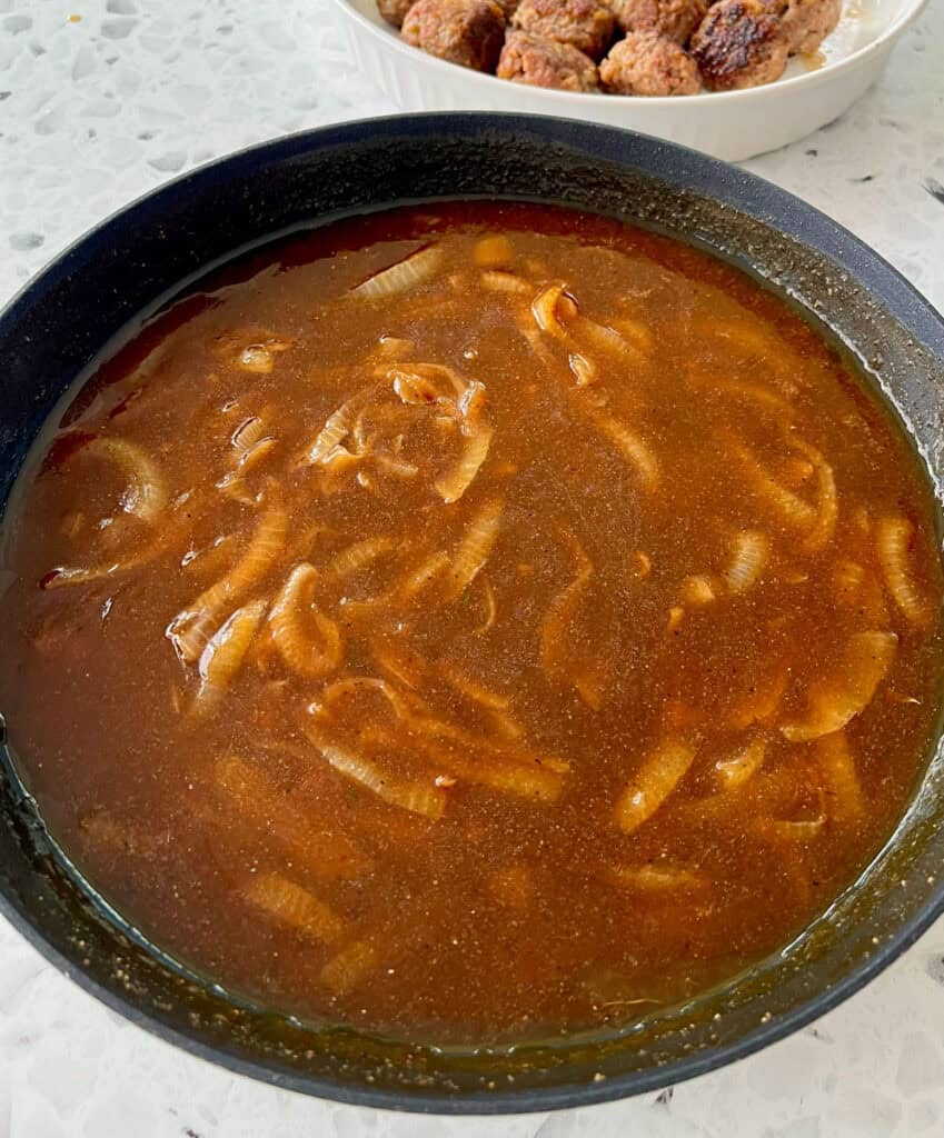 A pan of sauce and a plate of meatballs.