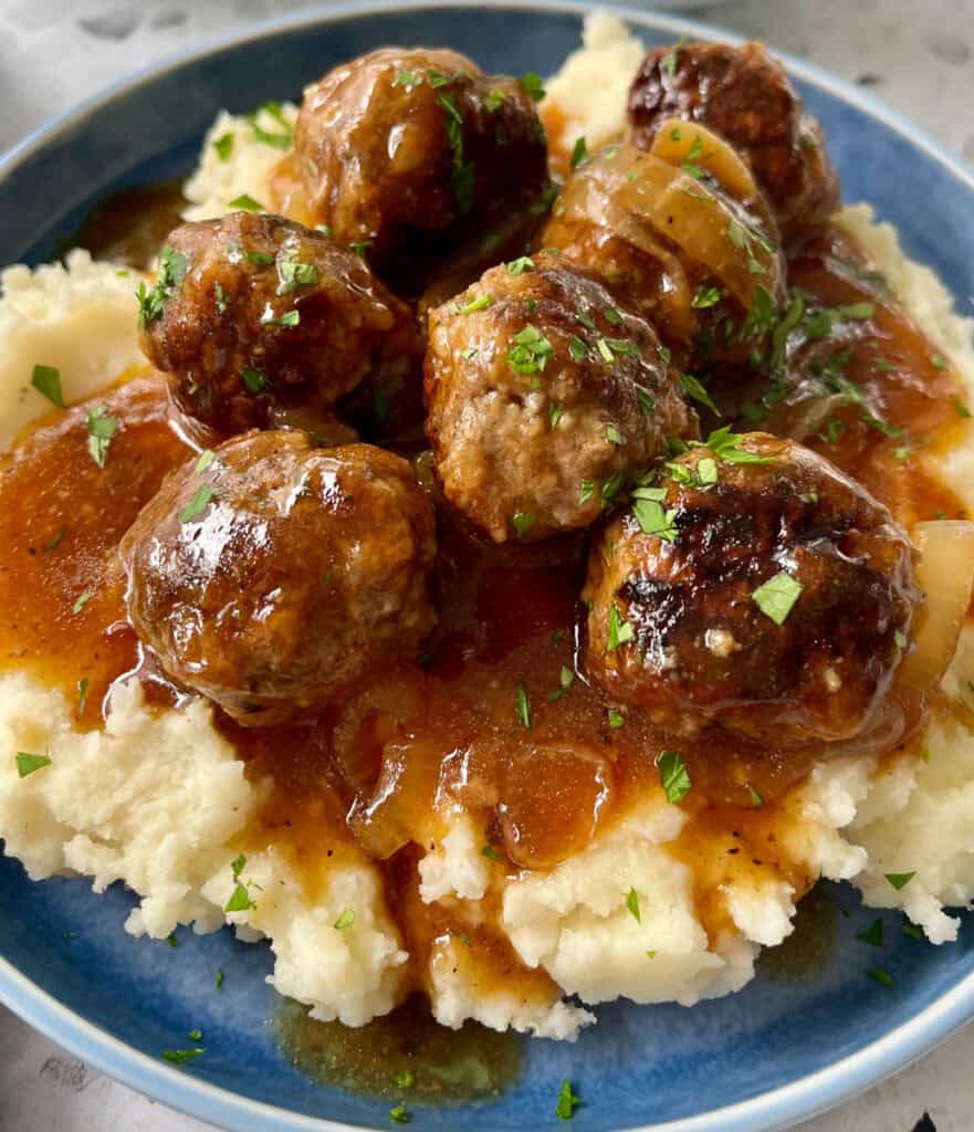 A plate of meatballs and mashed potatoes with gravy.