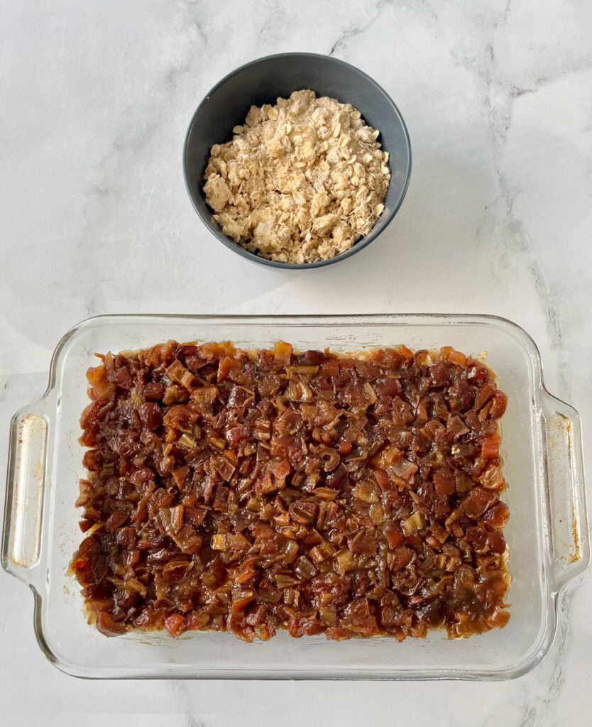 A glass baking dish filled with chopped up dates and a bowl of oats.