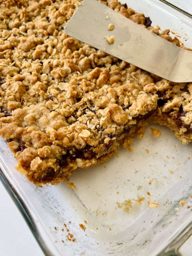 A glass baking dish with oatmeal bars and a spatula in it.