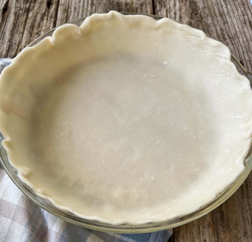 A pie crust in a glass pie dish.