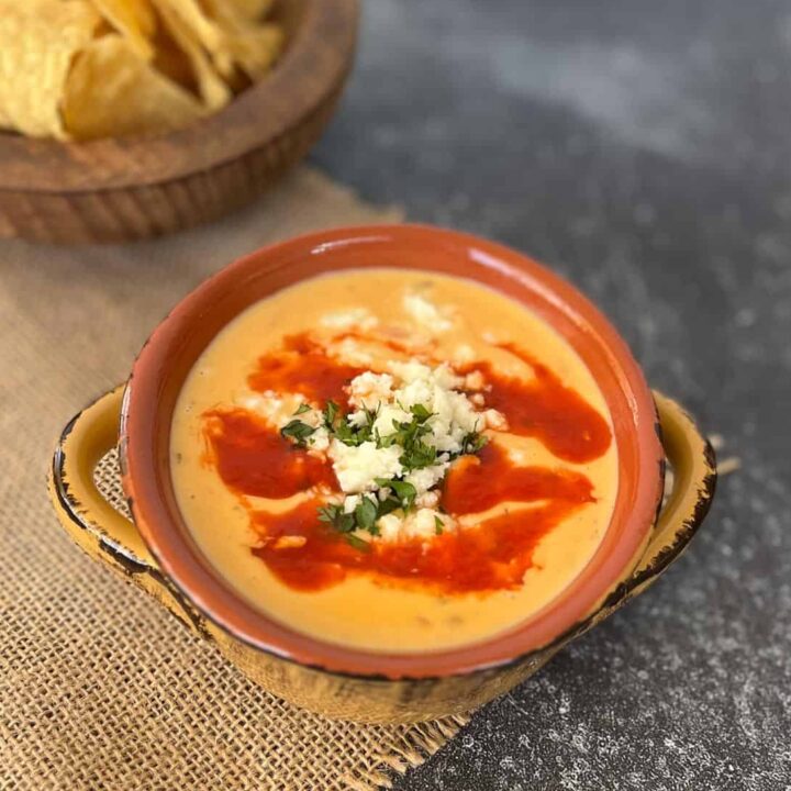 Mexican cheese dip in a bowl with chips.
