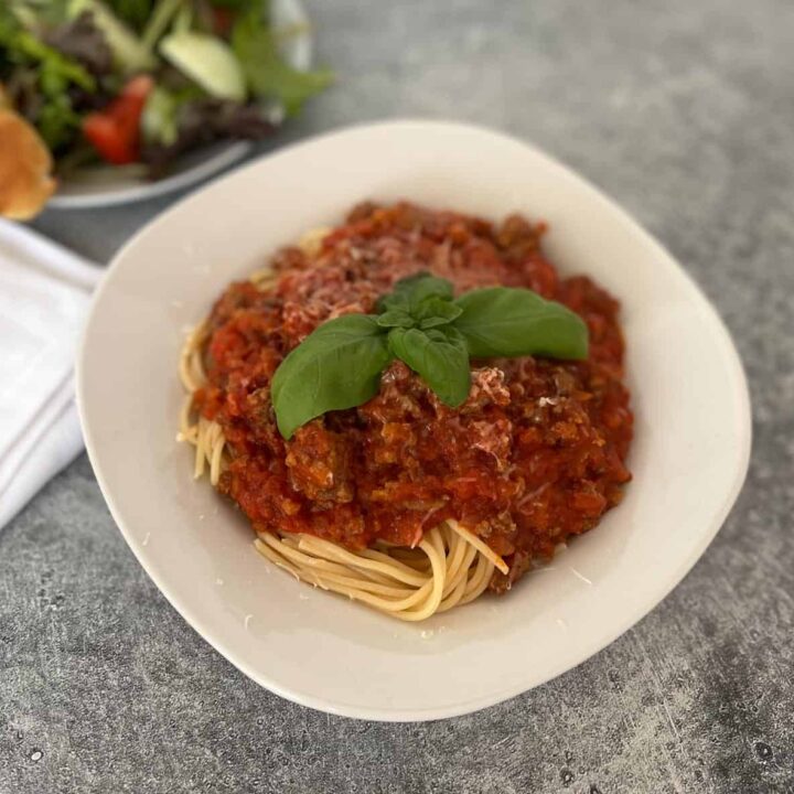 Spaghetti with meat sauce and basil.