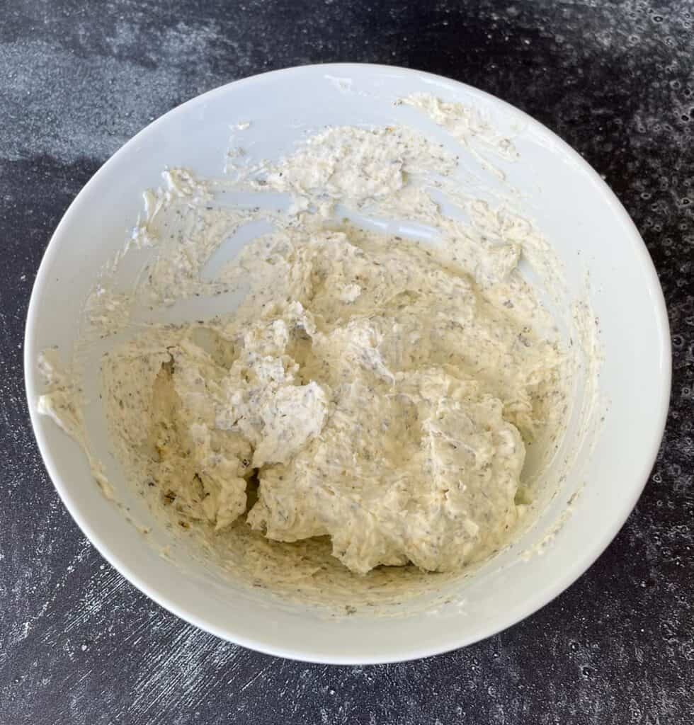 A bowl of cream cheese with some ingredients in it.