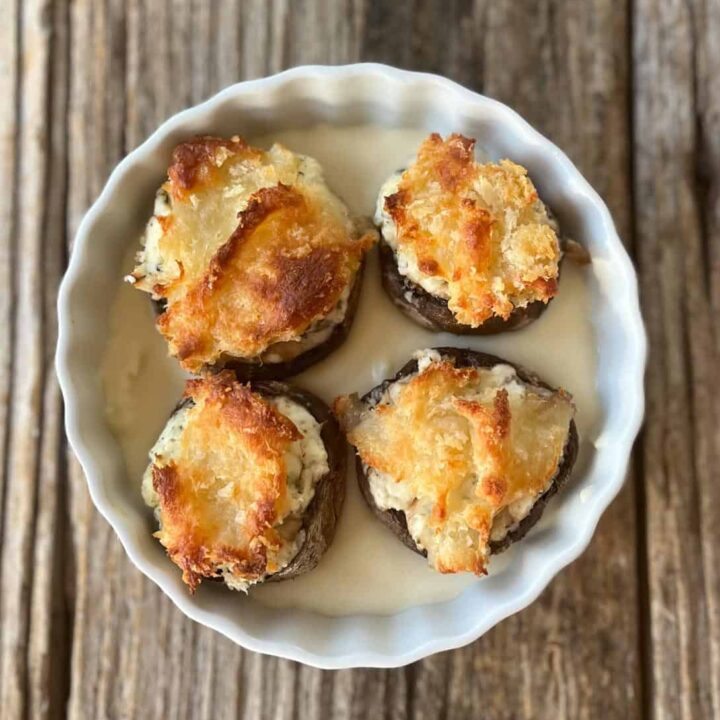 Stuffed mushrooms in a white bowl on a wooden table.