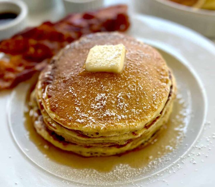 A stack of pancakes with butter and syrup on top.