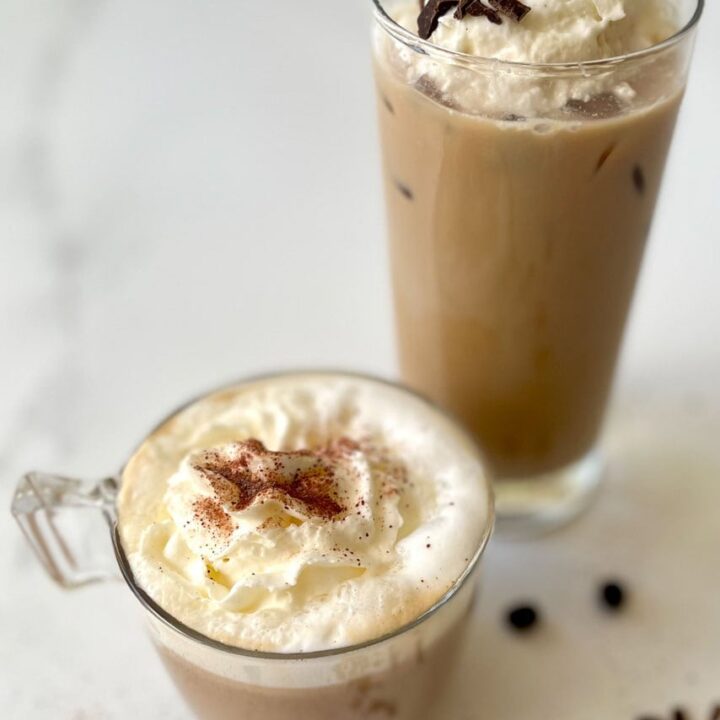 a glass cold of coffee with whipped cream and chocolate chips and a cup of hot coffee.