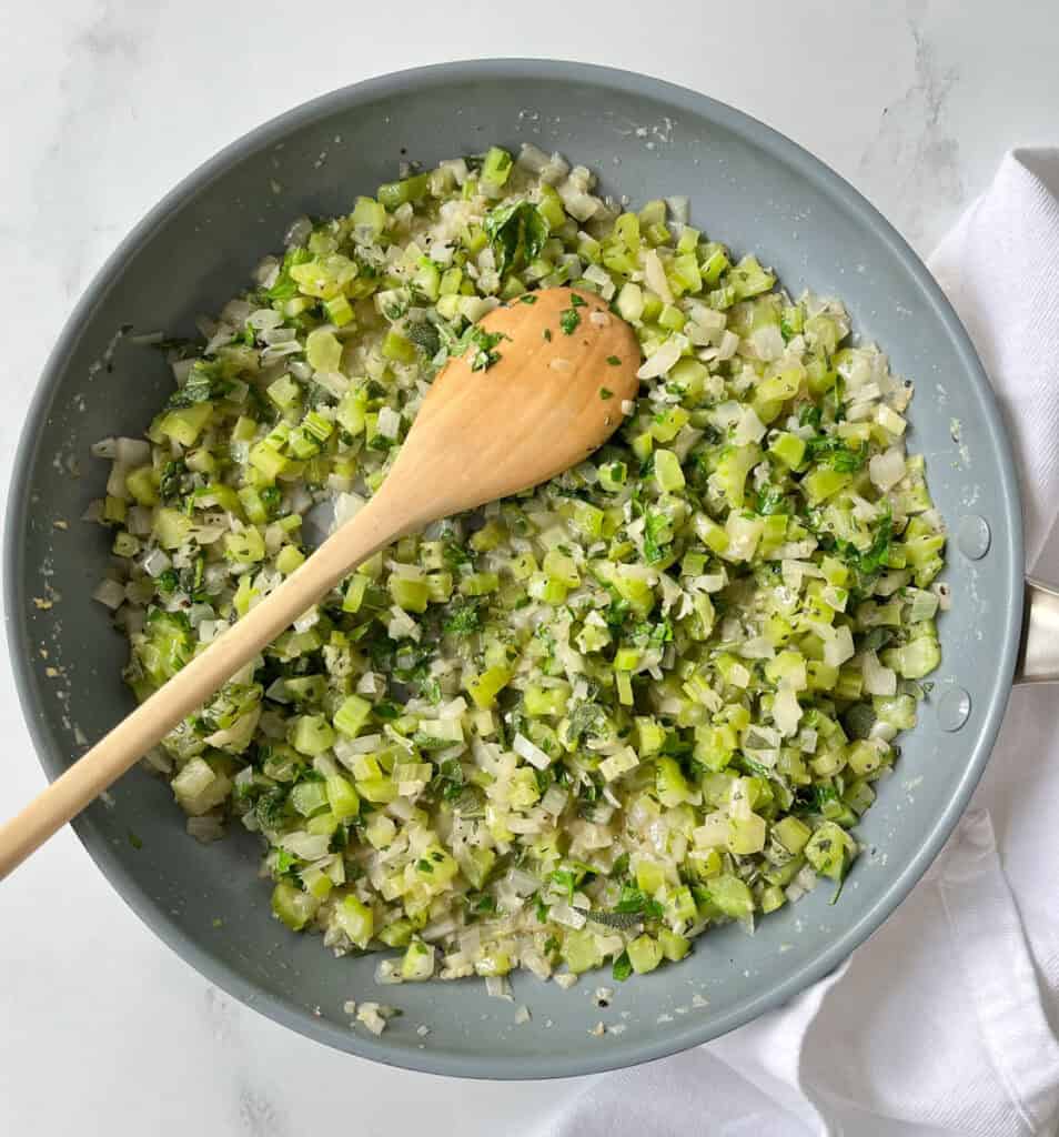 A pan filled with chopped vegetables and a wooden spoon.