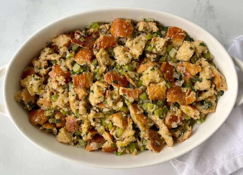 A clear bowl filled with stuffing and vegetables.