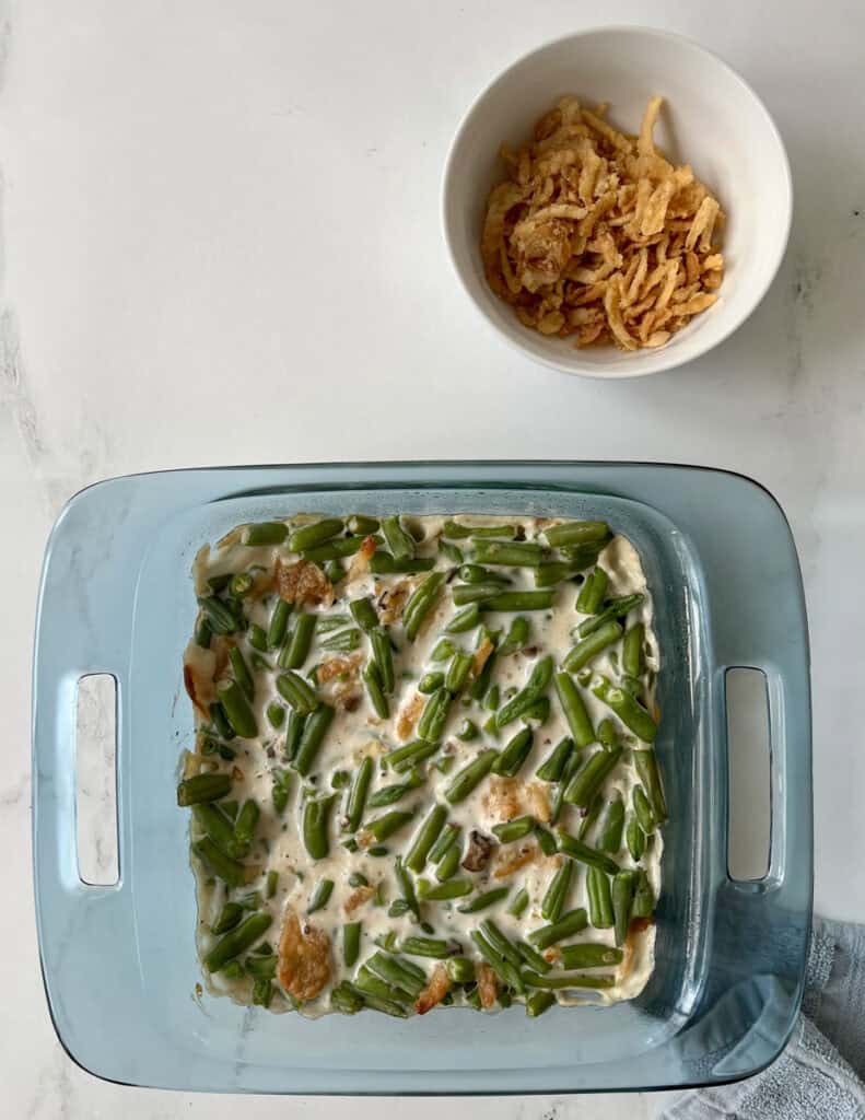 Unbaked Green bean casserole in a blue casserole dish.