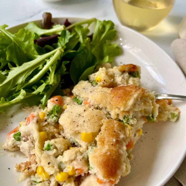 A plate of chicken pot pie with a fork and a salad.