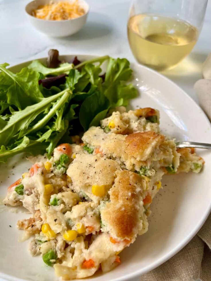 A plate of chicken pot pie with a fork and a salad.