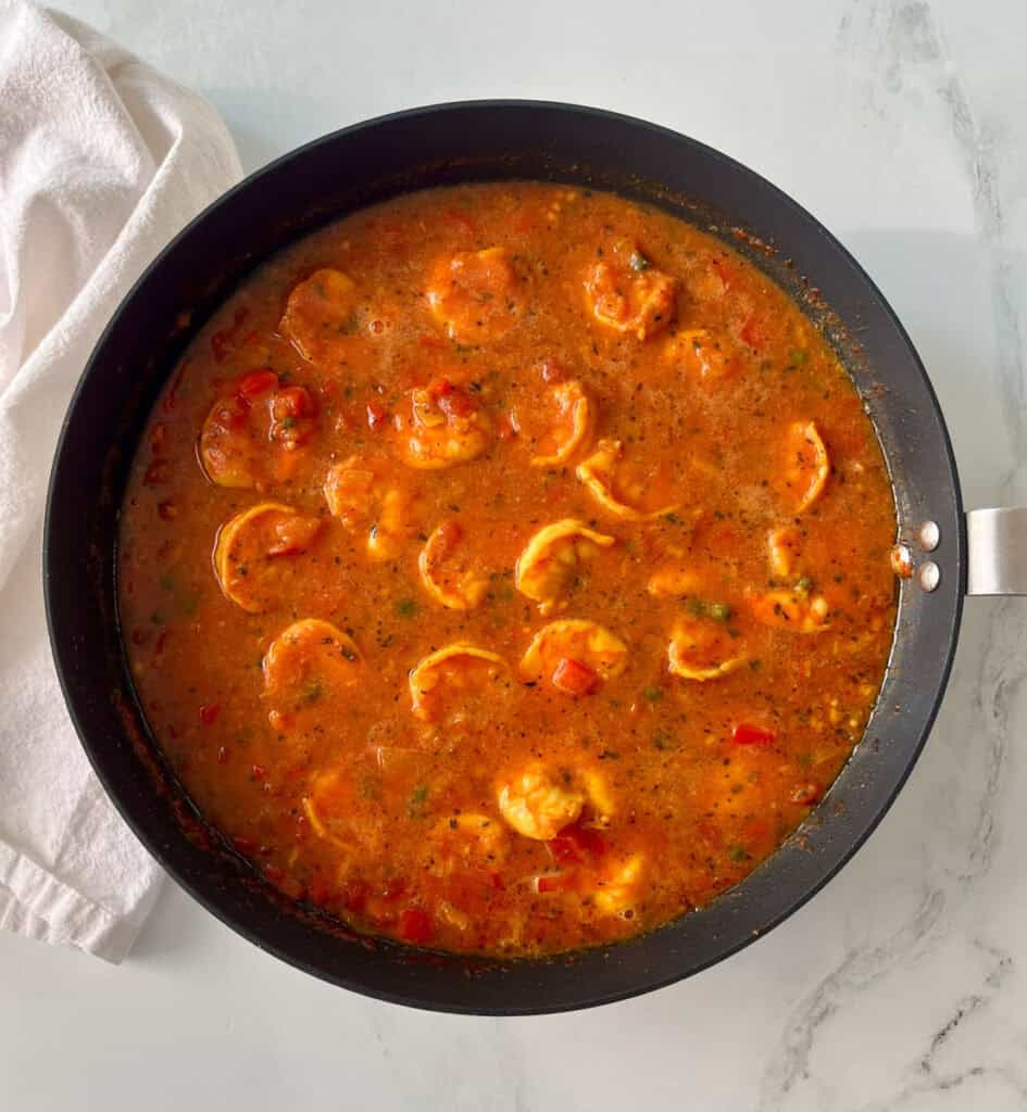 A pan filled with shrimp and tomato sauce.