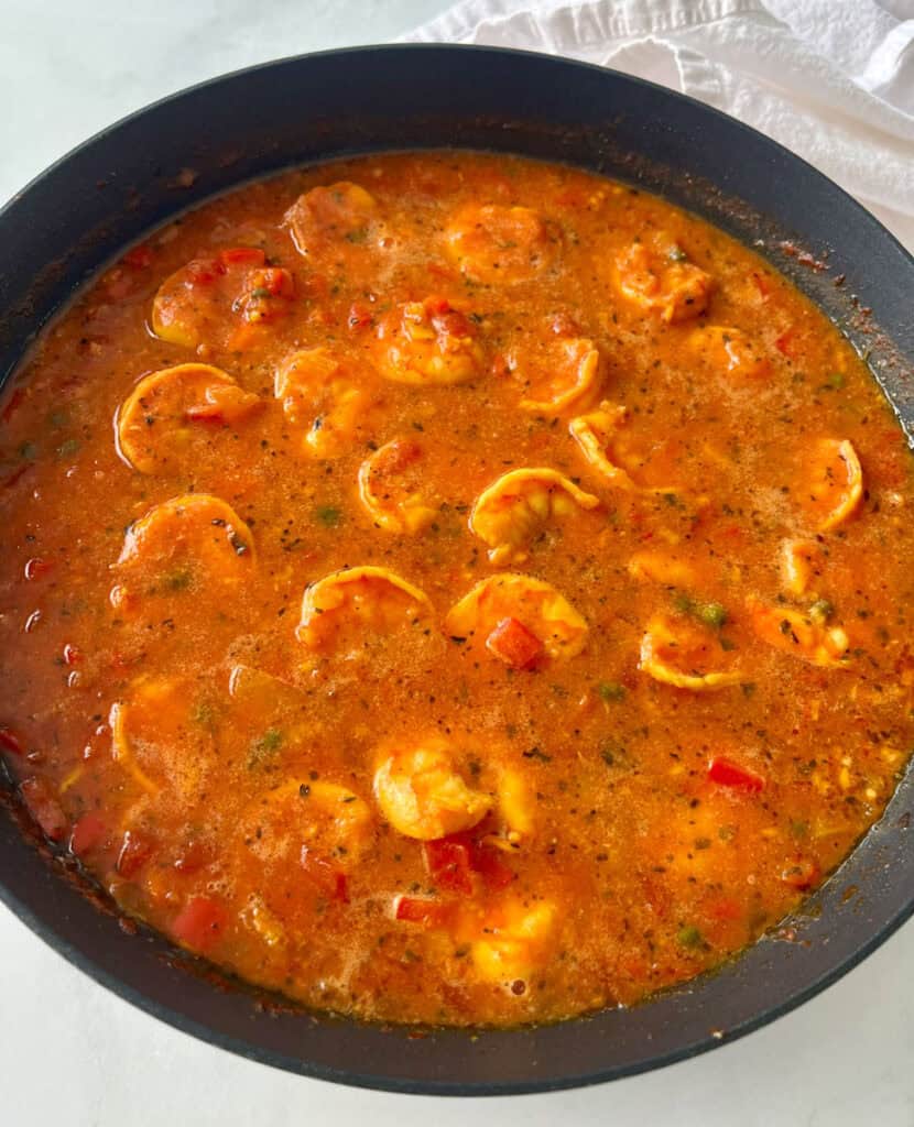 A pan filled with shrimp and tomato sauce.