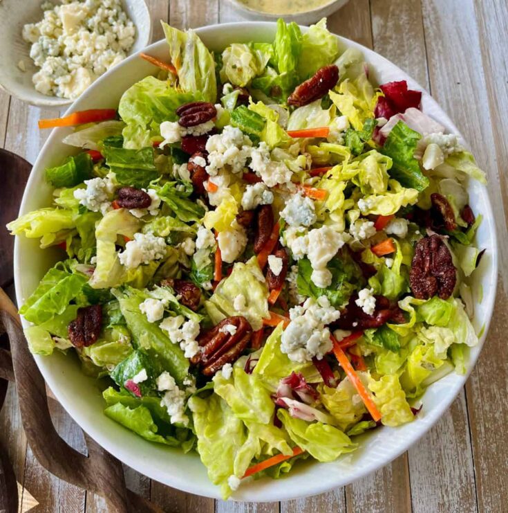 A salad with carrots, lettuce, and pecans.