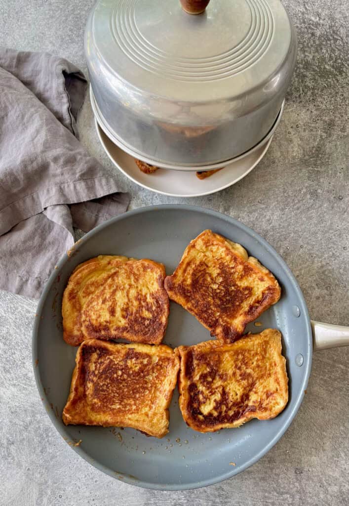 French toast in a pan and a covered plate.