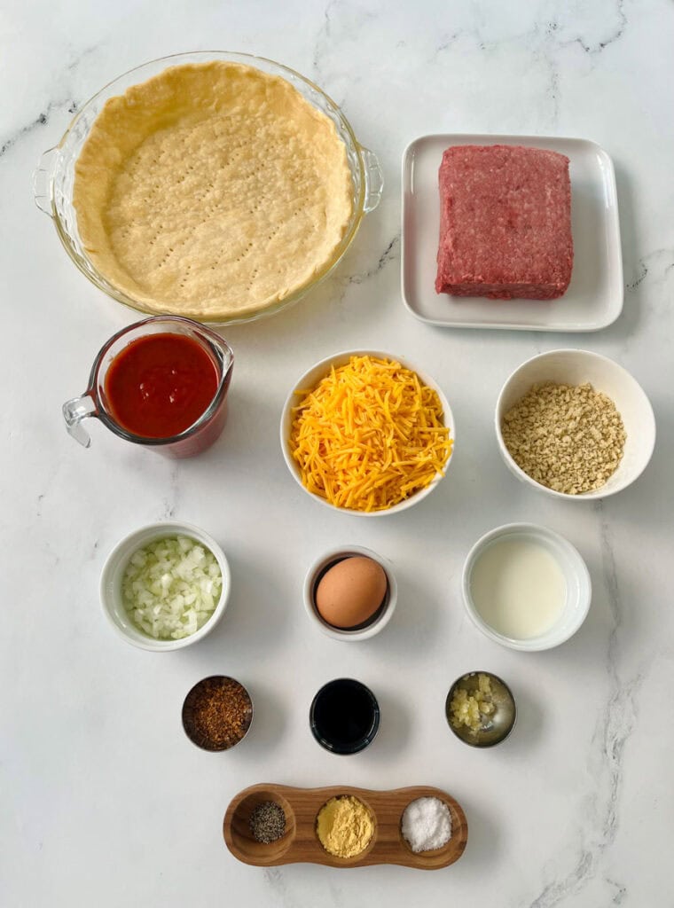 Ingredients for a meat and cheese pie on a white counter.