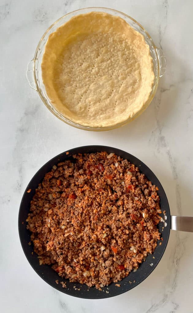 A pan with ground meat and a pie crust.