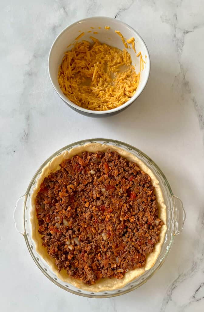 A pie crust with ground beef and cheese.
