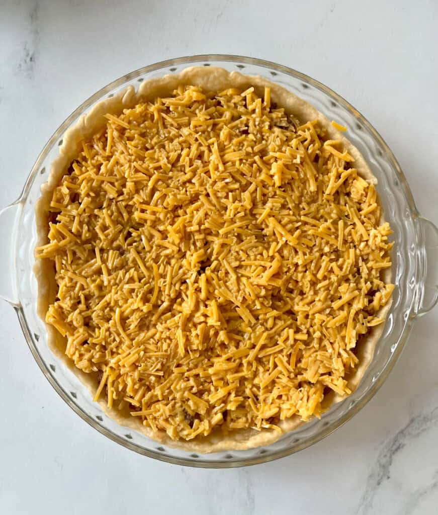 A pie crust with shredded cheese in it.