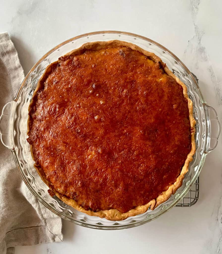 A pie crust with shredded cheese in it.
