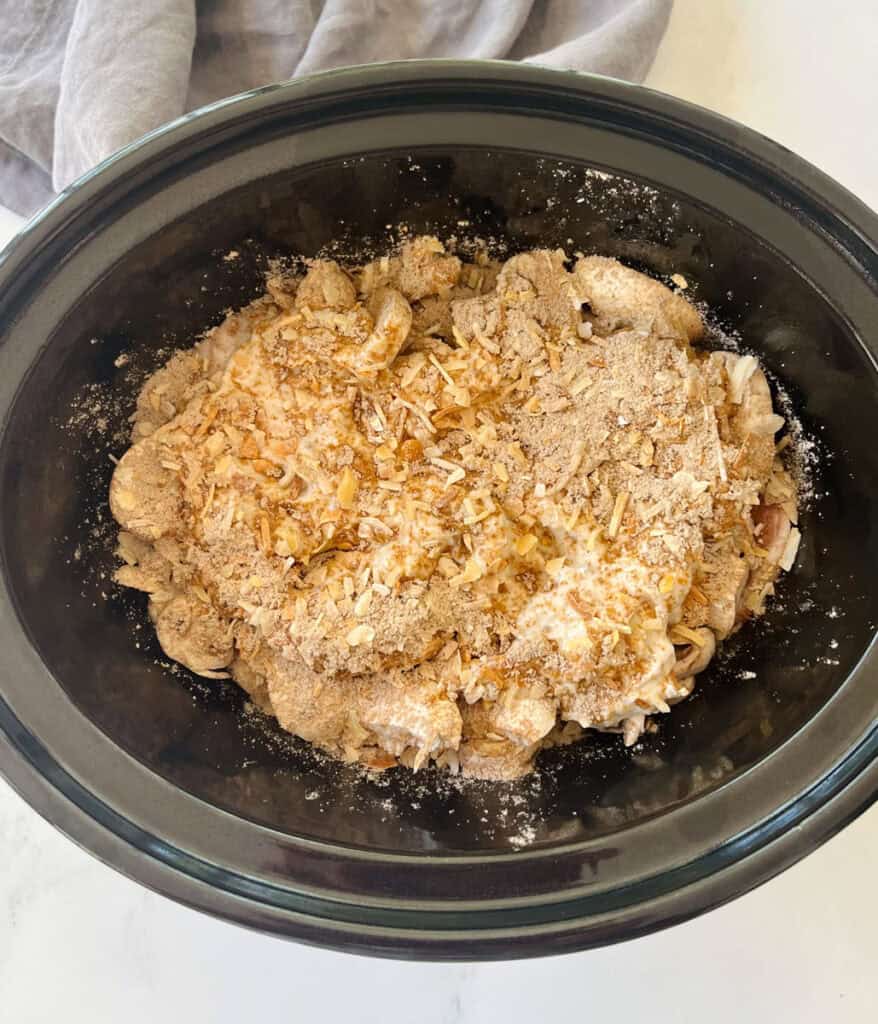 A slow cooker filled with pork chops, mushrooms, and seasonings.