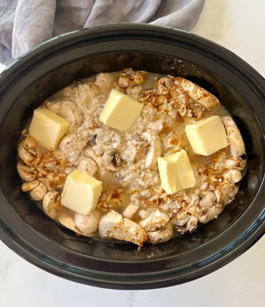 Pork chops, mushrooms, and seasonings in a slow cooker.