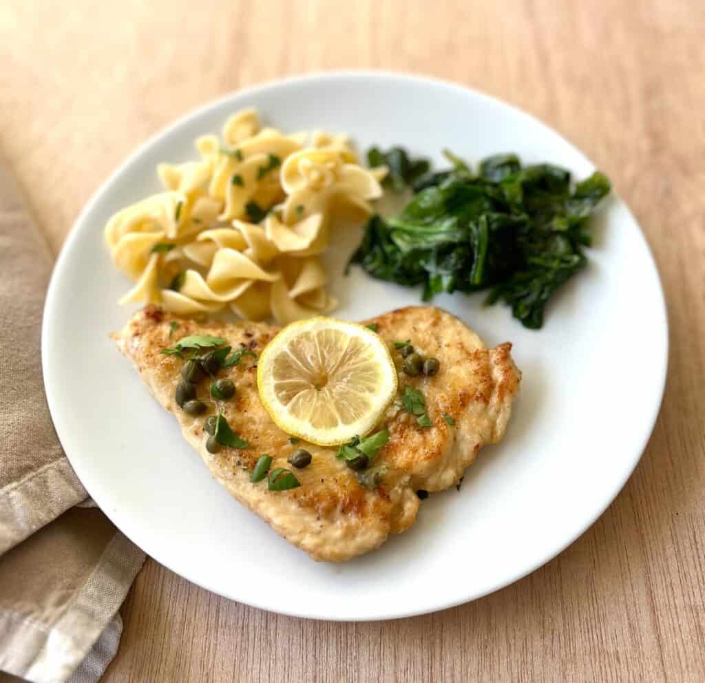 A plate with chicken, pasta and spinach.