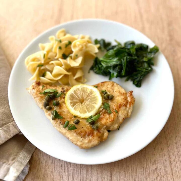 A plate with chicken, pasta and spinach.