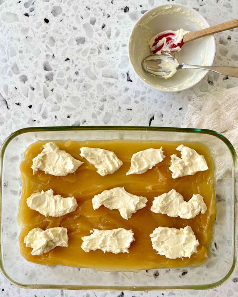 A glass baking dish filled with whipped cream cheese and lemon curd.
