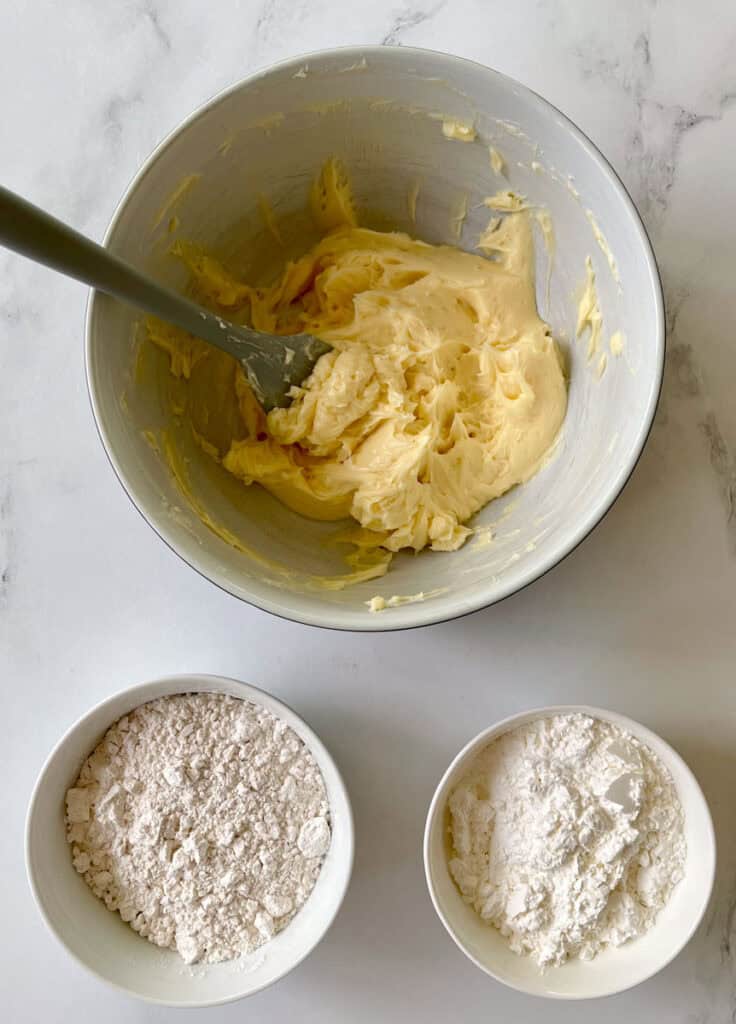 Bowls of flour, butter and sugar on a white counter.