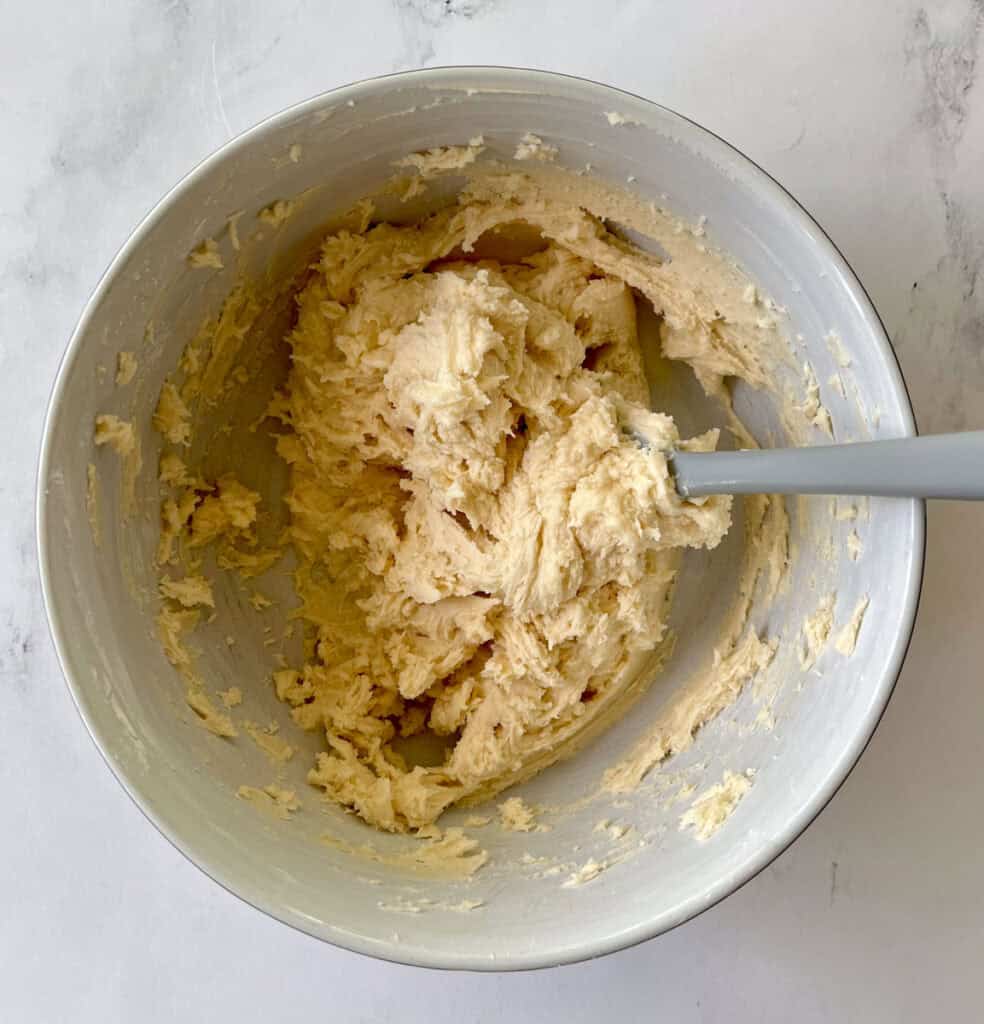 A bowl of batter with a spoon in it.