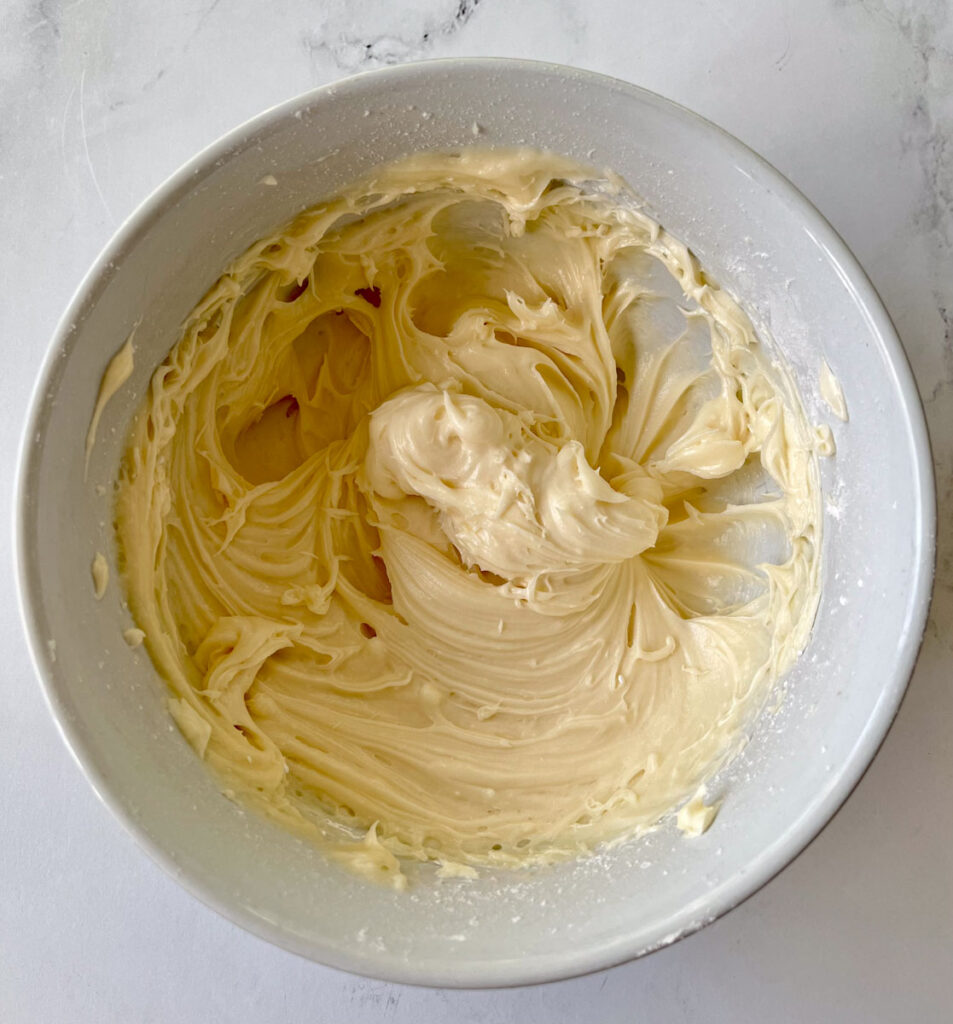 A bowl of butter cream frosting on a white counter.