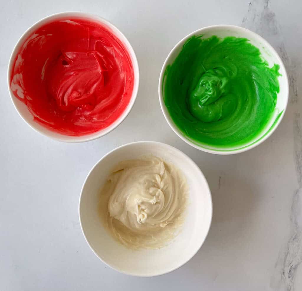Three bowls of red, green and white frosting.