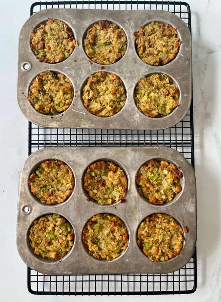 Two muffin pans filled with stuffing on a wire rack.