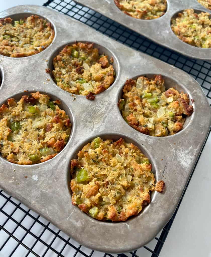 A muffin pan filled with stuffing muffins on a wire rack.