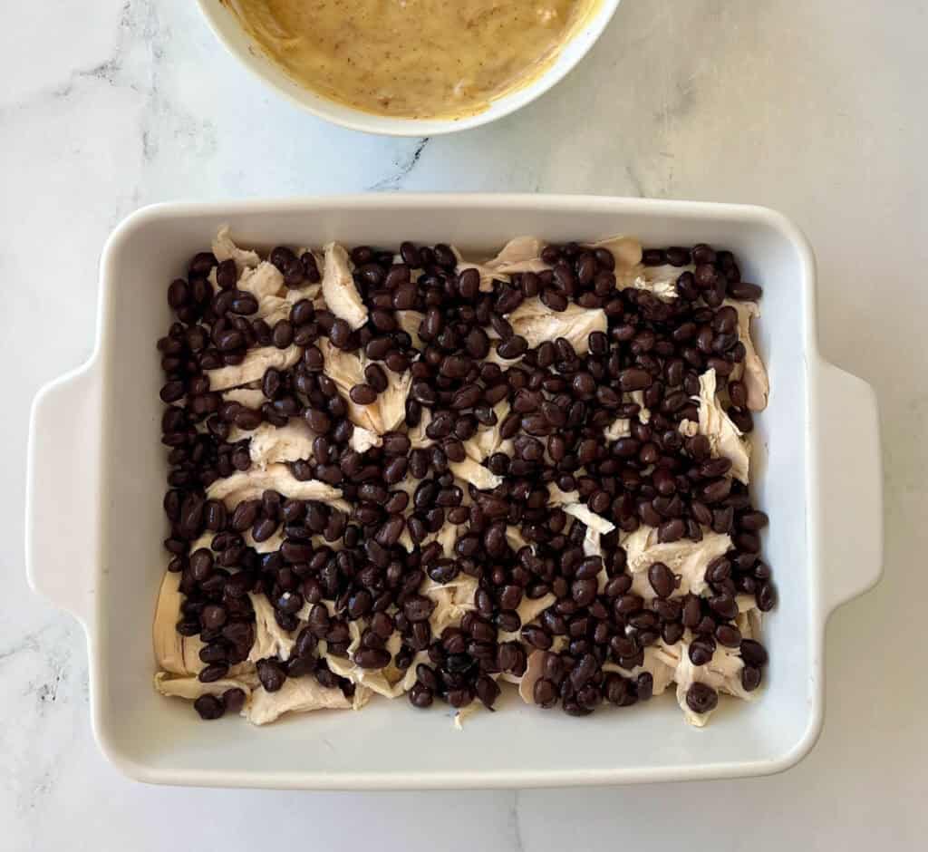 Chicken and black beans in a baking dish.