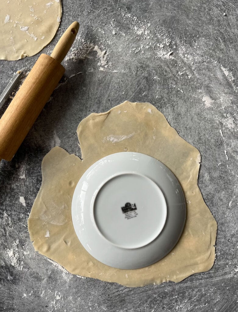 A rolling pin and a plate with dough on it.